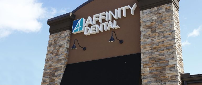 A sign on the front of a building that says Affinity Dental. Learn more about us and our office.