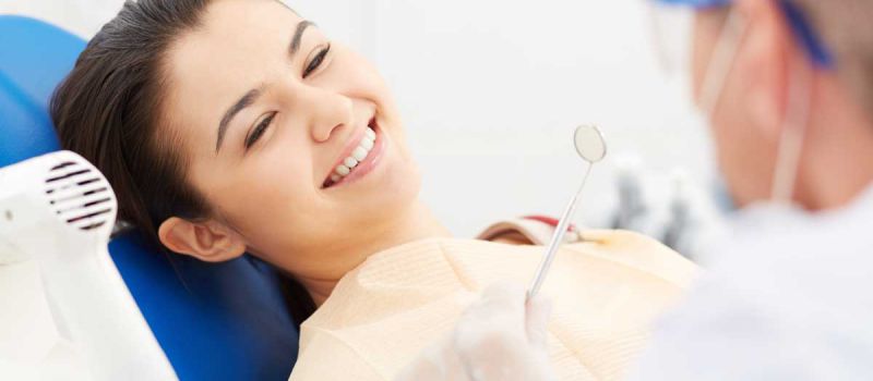 A woman in a dentists chair smiling.