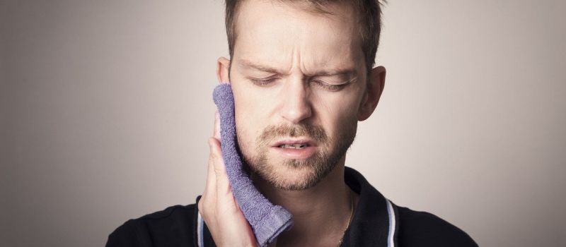 A man holding his jaw in pain.